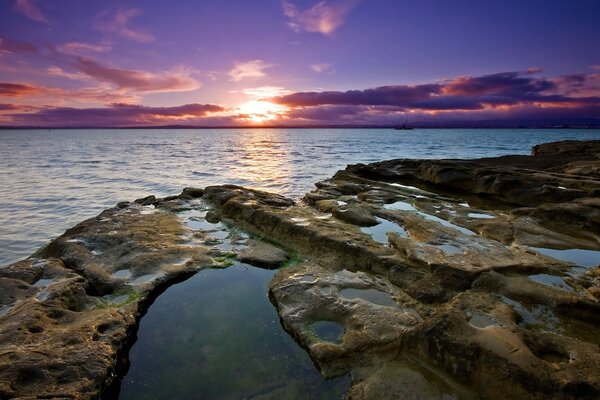 Puesta de sol con vistas a la costa rocosa y la superficie del agua