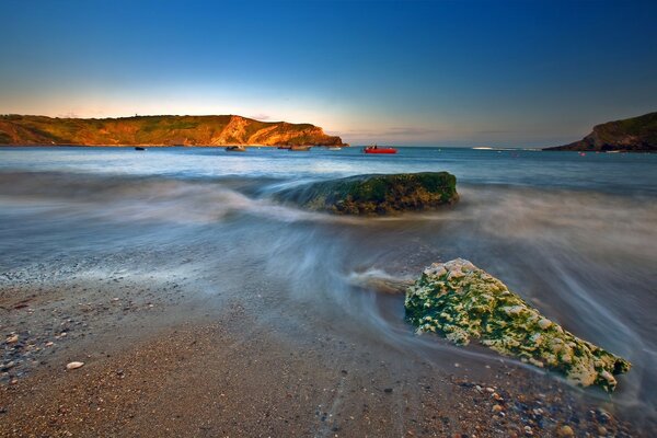 Waves crash against the rocks and roll onto the beach