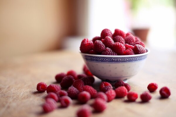 Raspberries in a plate on a wooden table