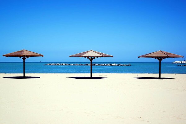 Three beach umbrellas on the background of the sea