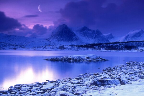 Water by moonlight surrounded by snowy mountains