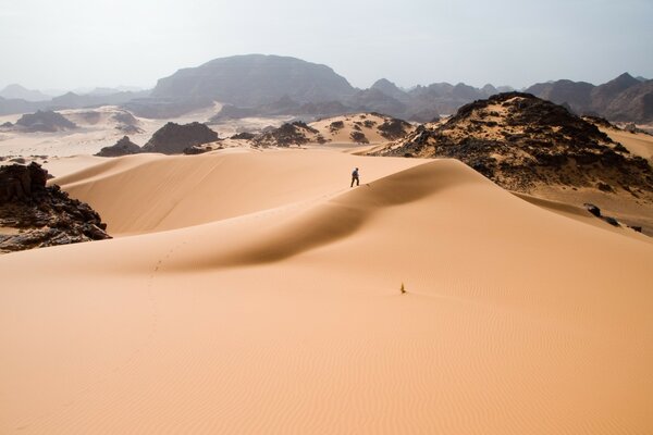 Человек в пустыни идет по песку