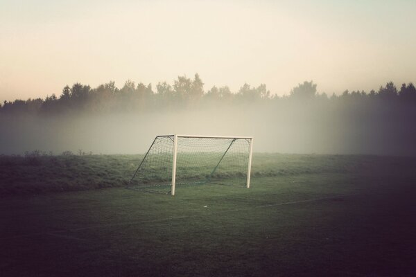 Campo de fútbol tupido, campo de fútbol por la mañana, puerta de fútbol en la niebla