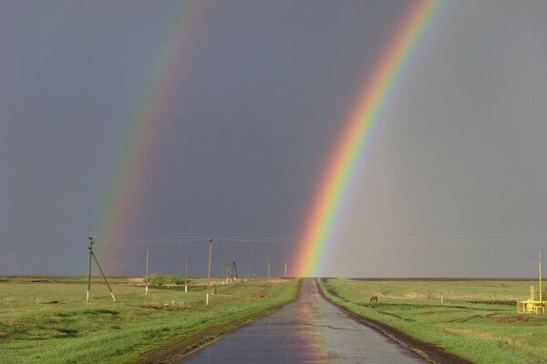 Arco iris doble en el camino en el campo