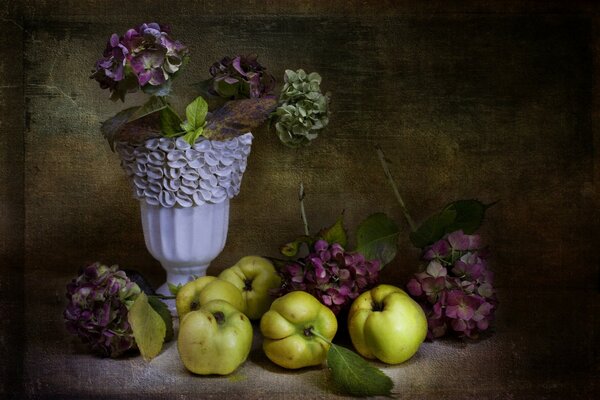 Äpfel mit Blumen in einer Vase auf dem Tisch