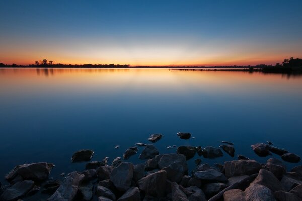 Ein See in einem wunderschönen Sonnenuntergang. Steine am See