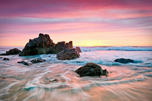 Sunrise on a sandy beach with rocks