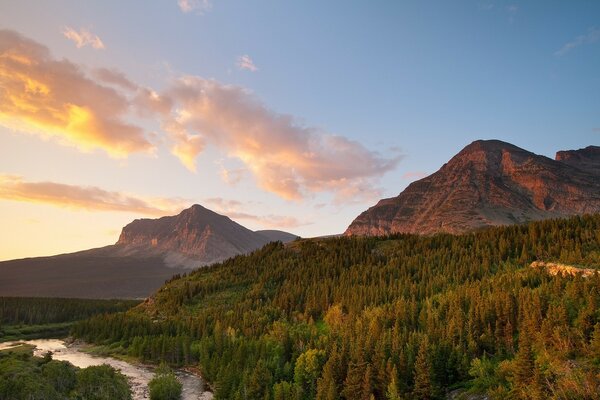 Landscape of mountains and trees against sunset clouds