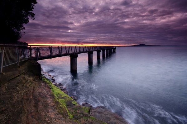 Cielo púrpura. Muelle a orillas del mar azul