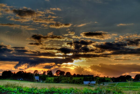 Schöne Wolken über dem Dorf und dem grünen Feld