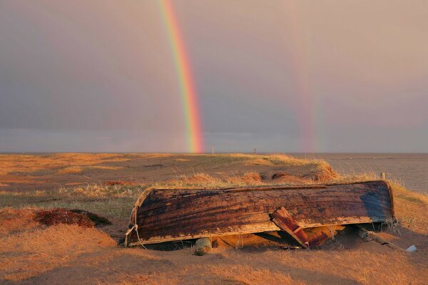 Doppelter Regenbogen am verlassenen Boot