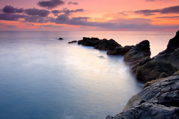 Ozean am Fuße der Klippen, Felsen bei Sonnenuntergang, Wasser im Ozean