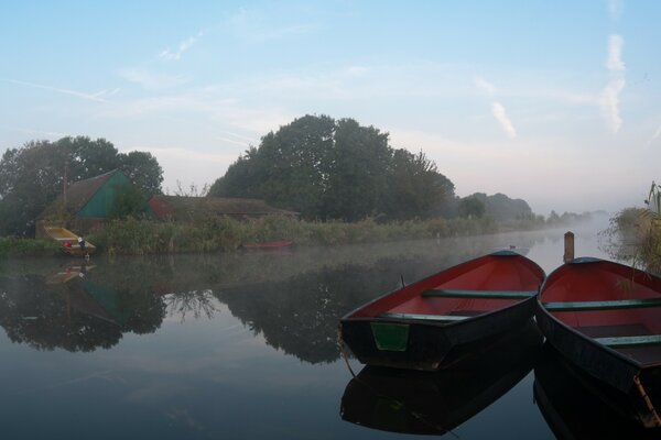 2 bateaux au milieu de la rivière dans le brouillard