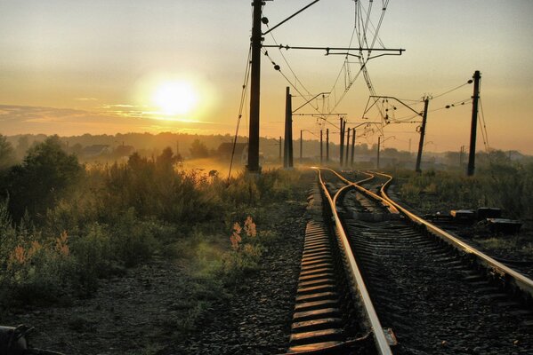 Chemin de fer dans le brouillard au coucher du soleil