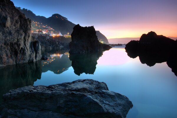 Ciudad brillante en el fondo de las rocas, el mar y la cálida tarde