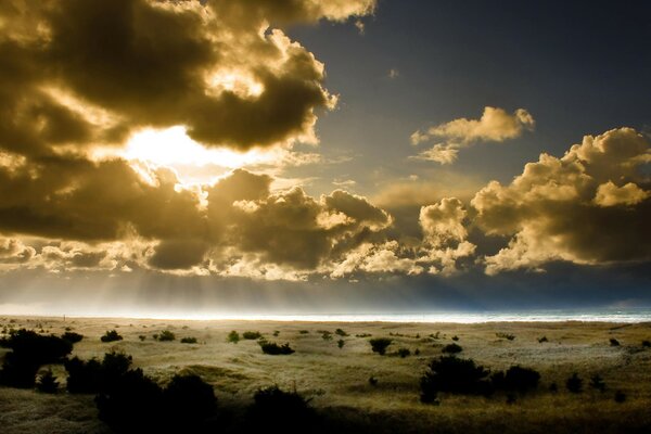 Cielo oscuro con nubes. Los rayos del sol a través de las nubes. Horizonte