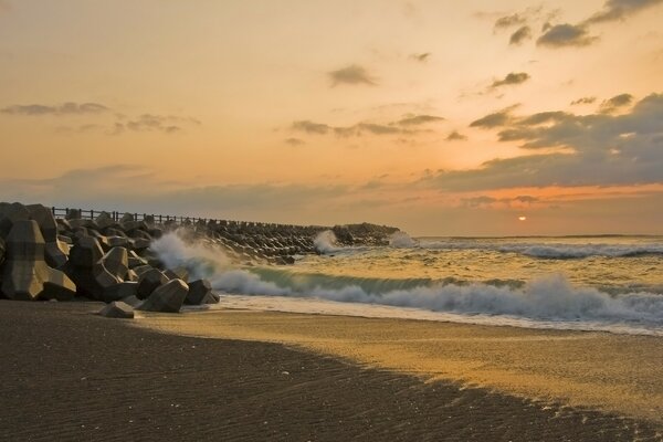 Les vagues battent sur le quai au coucher du soleil