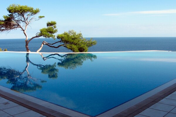 Swimming pool with clear water on the background of the endless sea