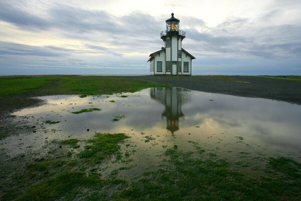 Faro sulla riva e pozzanghere