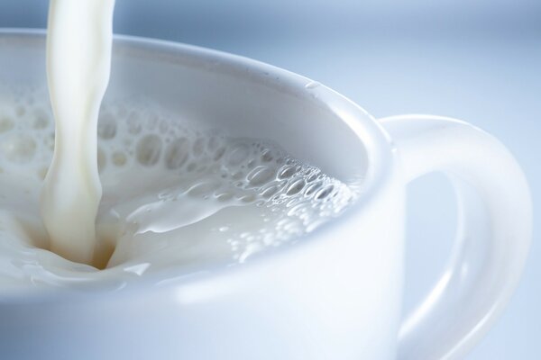 A trickle of milk pours into a white mug