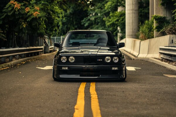 BMW E30 negro en el frente de la carretera