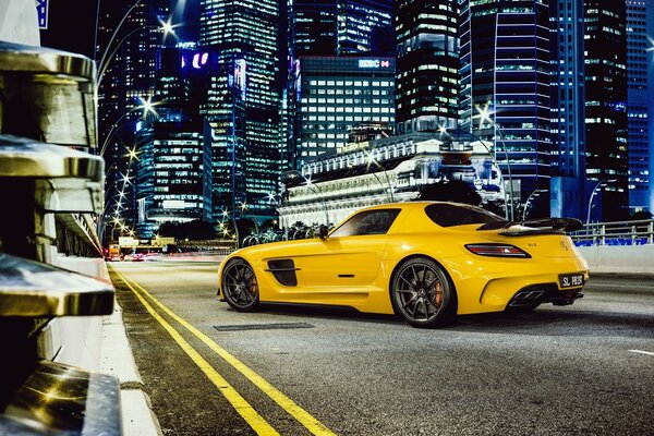 Mercedes gialla sullo sfondo dei grattacieli della città notturna