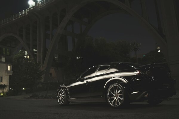 Mazda noire dans la nuit sous le pont