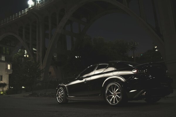 Czarna Mazda nocą pod przęsłem mostu
