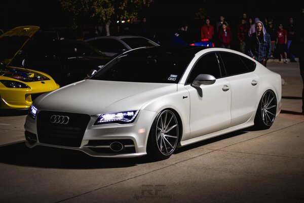 White Audi with tinted windows and headlights on