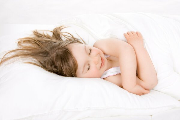 A child on a white pillow smiles in his sleep