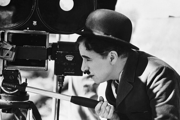 Charles Chaplin z wąsami w meloniku patrzy w kamerę