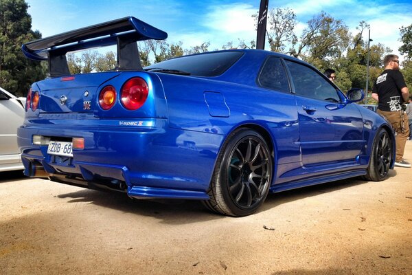 Blauer Nissan mit Tuning auf Sand und Himmel Hintergrund