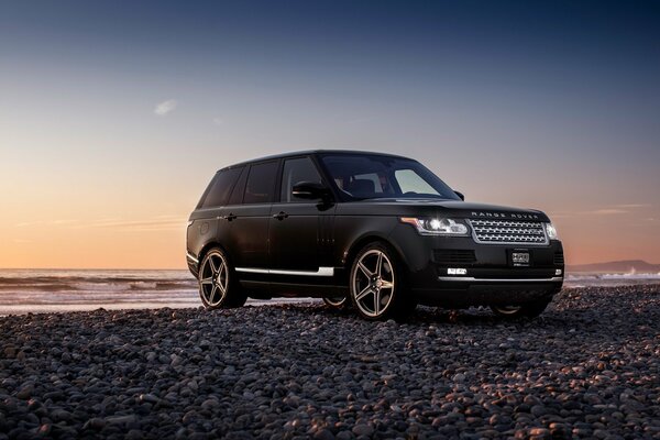 Jeep nera vicino al fiume al tramonto