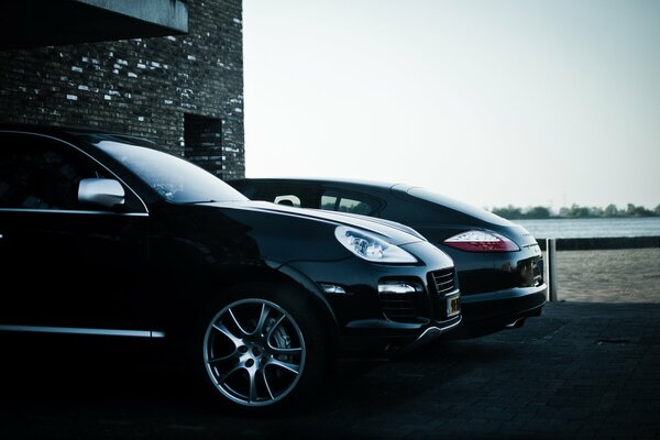 Elegante Porsche Cayenne negro estacionado en un edificio de ladrillo