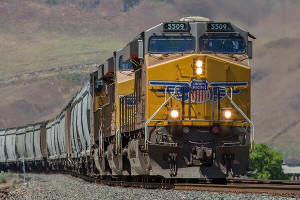 Gelbe Lokomotive zieht Waggons über die Schienen