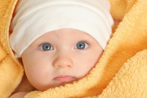 A beautiful baby with blue eyes in a yellow blanket