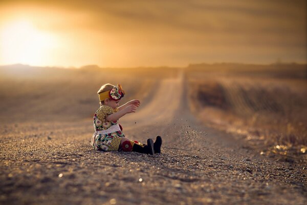 A little girl is sitting on the road