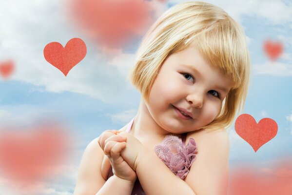 Kleines Mädchen lächelt auf dem Hintergrund der Herzen