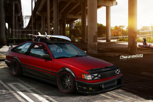 Red car in the parking lot under the bridge