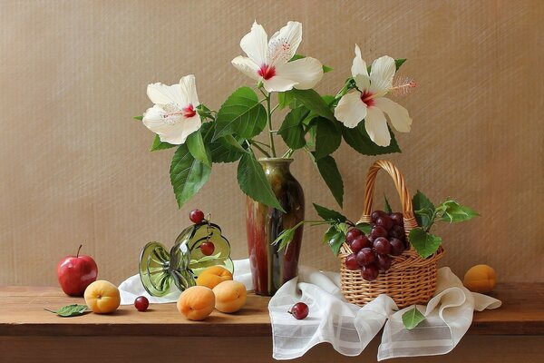 Stillleben aus zarten Blumen und reifen Früchten auf beigem Hintergrund