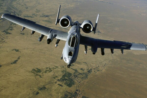 A big plane is flying over the yellow earth