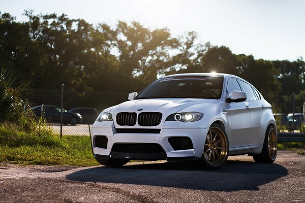 A white BMW casting a shadow on the road