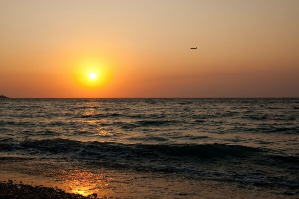 Sonnenuntergang am Meer mit Flugzeug am Himmel