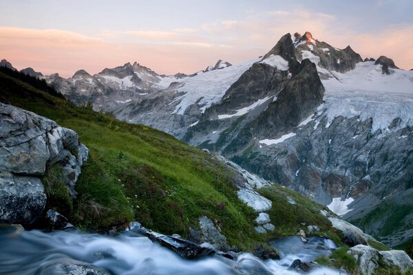 The mountains covered with grass are dusted with snow