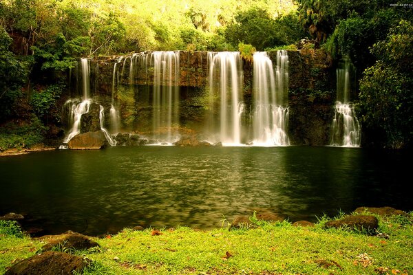 Lush summer landscape with waterfall and lake