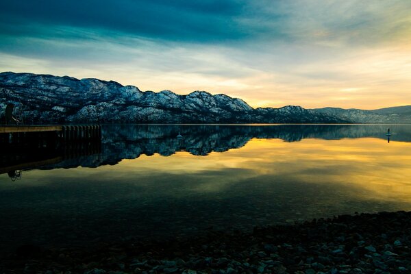 Sonnenuntergang vor dem Hintergrund der Berge und des Sees