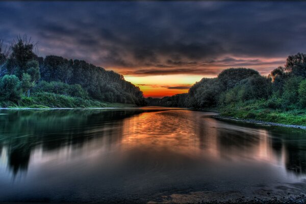 Clouds over the banks of the river at sunset