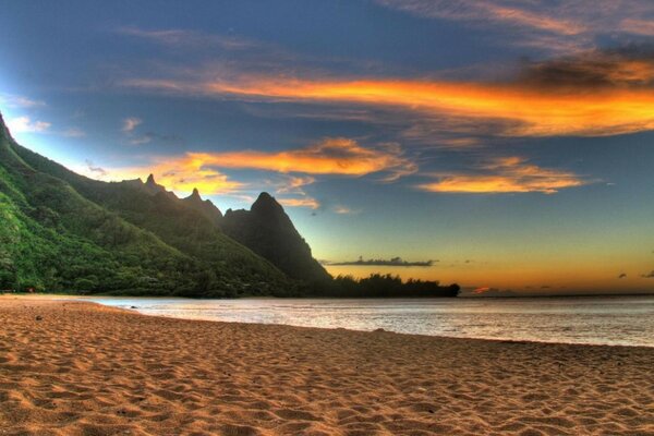 The beach at sunset against the backdrop of mountains and the sea