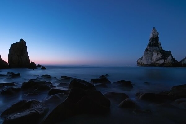 Rocas inusuales en el mar al anochecer