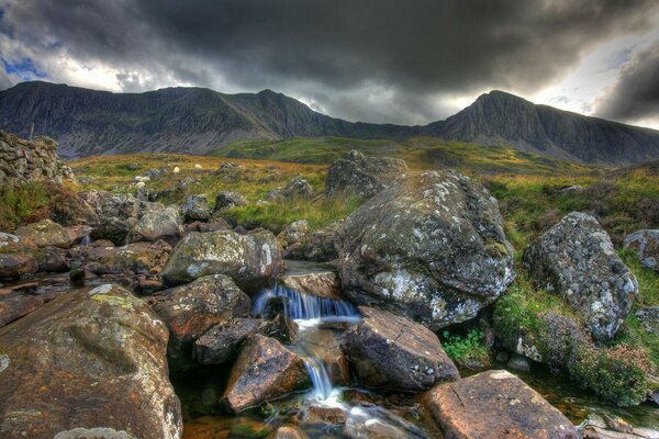 Río de montaña en medio de montañas y cielos oscuros